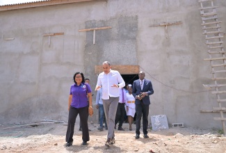 Minister of Health and Wellness, Dr. the Hon. Christopher Tufton (centre) speaks with Senior Medical Officer at the Bustamante Hospital for Children in Kingston, Dr. Michelle-Ann Richards Dawson (left), following a tour of the overnight suite at the hospital, which is under construction, on Thursday (May 1).  

