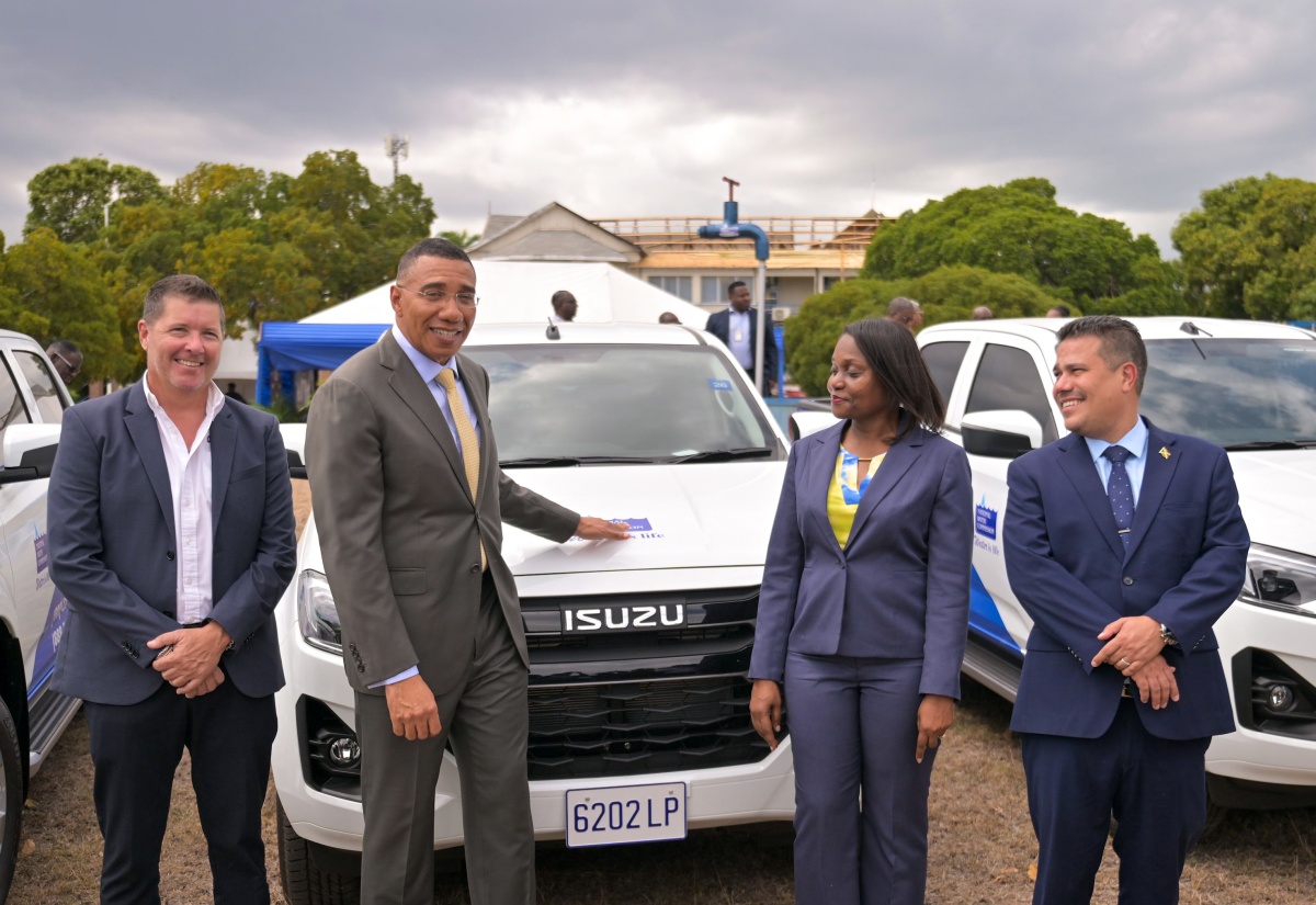 Prime Minister, Dr. the Most Hon. Andrew Holness (second left), points to the National Water Commission (NWC) logo on one of the 30 new pickup trucks that have been acquired by the entity to improve its service delivery to customers. Occasion was the official handover ceremony at the NWC