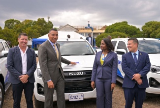 Prime Minister, Dr. the Most Hon. Andrew Holness (second left), points to the National Water Commission (NWC) logo on one of the 30 new pickup trucks that have been acquired by the entity to improve its service delivery to customers. Occasion was the official handover ceremony at the NWC