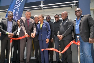 Prime Minister, Dr. the Most Hon. Andrew Holness (second left), along with Minister of Legal and Constitutional Affairs, Hon. Marlene Malahoo Forte (fifth right), and Executive Chairman, Guardsman Group of Companies, Kenneth Benjamin (fourth left), cuts the ribbon to officially open the Guardsman Cyber Intelligence Security Operations Centre (SOC) at 14-16 Balmoral Avenue in Kingston on Wednesday (May 14). They are joined by Minister of State in the Ministry of Foreign Affairs and Foreign Trade, Hon. Alando Terrelonge (left), employees of Guardsman Group of Companies, and other guests.