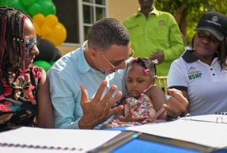 Prime Minister, Dr. the Most Hon Andrew Holness, interacts with little Zahira Mitchell, who is the granddaughter of New Social Housing Programme (NSHP) beneficiary, Elaine Bennett (left).  Sharing the moment is Permanent Secretary in the Ministry of Economic Growth and Job Creation, Arlene Williams. The occasion was the handover of keys to Miss Bennett’s new home in Lloyd’s District, St. Thomas, on Thursday (May 15).

