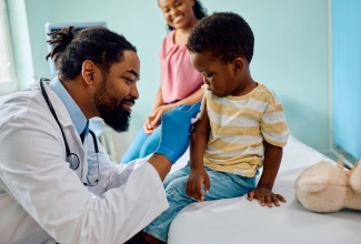 Pediatrician preparing arm of a small boy for vaccination at doctor