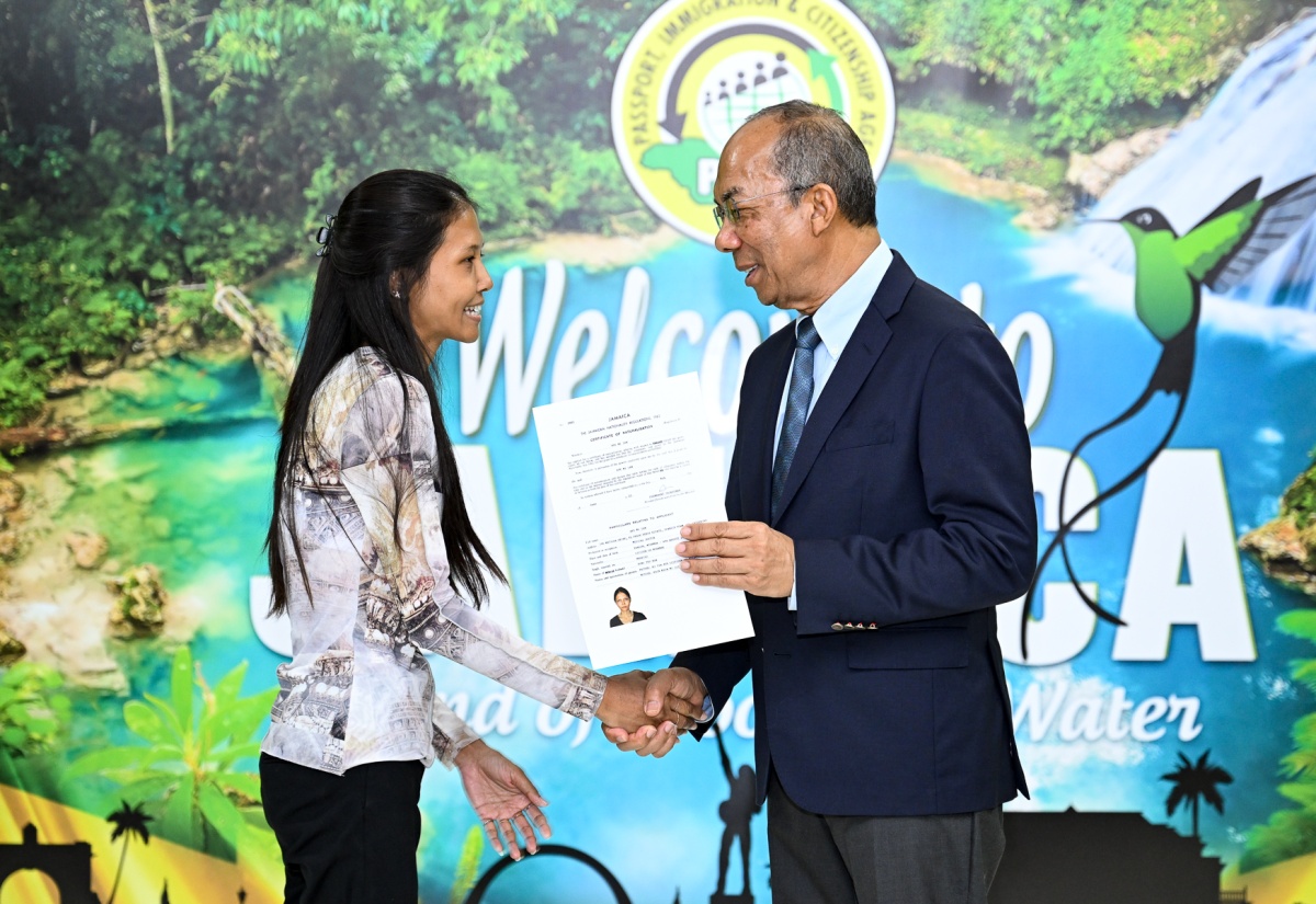 Deputy Prime Minister and Minister of National Security, Hon. Dr. Horace Chang (right), presents new Jamaican citizen Aye Mi San with a certificate formalising her status, during today’s (June 6) citizenship ceremony at the Police Officers Club in St. Andrew.