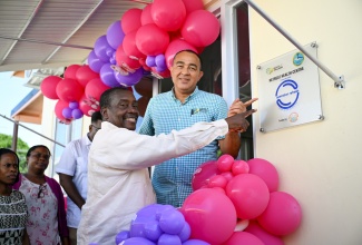 Minister of Health and Wellness, Dr. the Hon. Christopher Tufton (right), and Member of Parliament for St. Mary Western, Hon. Robert Montague, point to a sign at the upgraded Retreat Health Centre in St. Mary, on June 20.