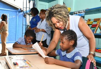 Minister of Education, Skills, Youth and Information, Senator Dr. the Hon. Dana Morris Dixon, assists a student of Higholborn Street Basic School in Kingston Central during a recent visit.