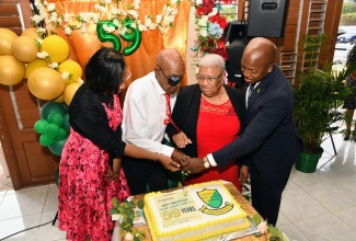 Minister of Labour and Social Security, Hon. Pearnel Charles Jr. (right); Acting Permanent Secretary in the Ministry, Dione Jennings (left), and two NIS pensioners, Ruby Gordon-Young and Keith Powell, cut the cake at the National Insurance Scheme (NIS) 59th Anniversary Church Service, held at the Yallahs Baptist Church, in St. Thomas, on June 1.