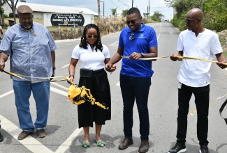 Minister without Portfolio in the Ministry of Economic Growth and Job Creation with responsibility for Works, Hon. Robert Morgan (second right), cuts the ribbon to open the rehabilitated Holland to Bounty Hall roadway in Northern Trelawny on Friday (June 6). He is assisted by Member of Parliament for Trelawny Northern, Tova Hamilton (second left). Looking on are Project Manager, National Works Agency (NWA), Caswell Whyte (left) and Regional Manager (Western Region), NWA, Robert Francis.