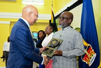 Governor-General, His Excellency the Most Hon. Sir Patrick Allen (left), presents Jamaica Information Service (JIS) Senior Reporter, Garfield Angus, with his award at the 2025 Governor-General’s Achievement Awards (GGAA) ceremony, held at King’s House on Thursday (June 26). Mr. Angus was the St. Catherine awardee in the over 35 age category. In the background are the St. Catherine awardees for the 18-24 years category, Shamoi Brown (second left) and in the 25 to 35 years category, Sherika Perkins.

