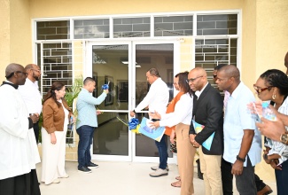 Health and Wellness Minister, Dr. the Hon. Christopher Tufton (seventh right), and Minister without Portfolio in the Ministry of Economic Growth and Job Creation, Hon. Matthew Samuda (fourth left), are joined by other stakeholders, as they cut the ribbon to mark the official opening of the new $383 million St. Ann Health Department Administrative Building on Friday (June 6).