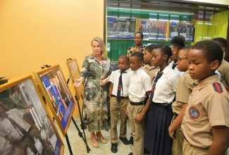 European Union (EU) Ambassador to Jamaica, Her Excellency Dr. Erja Askola (left), highlights some of the work undertaken by the EU in Jamaica to students of Franklin Town Primary School. The Ambassador and the students visited the National Library of Jamaica in Kingston, on Monday (June 23) to view the EU-Jamaica 50 Photographic Exhibition. Observing the moment is Curator and Senior Director of User Services and Conservation at the National Library, Tricia Lawrence Powell.

