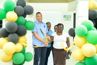 Prime Minister, Dr. the Most Hon. Andrew Holness (left) officially cuts the ribbon to hand over a New Social Housing Programme (NSHP) unit to beneficiary, Precious Eason (right) in Freeman