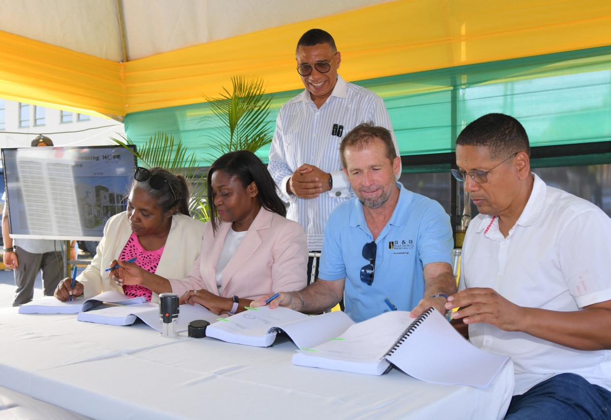Prime Minister, Dr. the Most Hon. Andrew Holness (standing, centre) witnesses the contract signing for the East Palms Housing Development during a ground-breaking ceremony on East Avenue in Kingston Central on Wednesday (June 4). Participating are (from left, seated) Chair, New Social Housing Programme (NSHP) Oversight Committee, Judith Robb Walters; Permanent Secretary, Ministry of Economic Growth and Job Creation, Arlene Williams; Operations Director, S&G Road Surfacing Materials Limited, Anthony J. Sampson, and Kingston Central Member of Parliament, Donovan Williams. The new development will replace the previous dwelling, which was destroyed by fire in July 2021, leaving a 13-member family homeless ever since.


