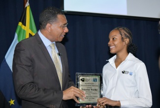 Prime Minister, Dr. the Most Hon. Andrew Holness (left), presents a plaque to Jamaica National Service Corps (JNSC) skills training participant, Valesha Burke, during the closing out ceremony for the first set of trainees under the Skills Track for Workforce Development, held on June 20 at the Jamaica Defence Force (JDF) headquarters, Up Park Camp, Kingston. Ms. Burke was the top participant in the programme’s Administrative Assistance course.

