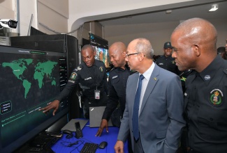 Deputy Prime Minister and Minister of National Security, Hon. Dr. Horace Chang (second right); Police Commissioner, Dr. Kevin Blake (right), and Head of the Jamaica Constabulary Force (JCF) Technology Branch, Assistant Commissioner of Police, Leonardo Brown (second left), listen as Sergeant C. Curtis explains aspects of the cyberthreat map during the opening ceremony for the JCF ‘Transformations – People, Quality and Technology Expo 2.0’ at the National Arena on Thursday (June 19).