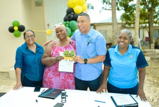 Prime Minister, Dr. the Most Hon. Andrew Holness (second right) presents New Social Housing Programme (NSHP) beneficiary, Sharon Hughes, with a social contract and the keys to her new home. Occasion was the handover ceremony for Ms. Hughes