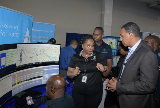 Prime Minister, Dr. the Most Hon. Andrew Holness (right), listens as Shauna-Kay Malcom (left) from the Police Emergency Communication Centre (PECC), outlines the technology utilised in surveillance and crime prevention and response. Occasion was a tour of the Jamaica Constabulary Force’s (JCF) ‘Transformations – People, Quality and Technology Expo 2.0,’ at the National Arena in Kingston on Friday (June 20).