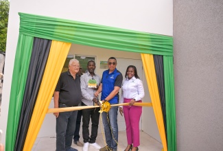 Prime Minister, Dr. the Most Hon. Andrew Holness (second right), cuts the ribbon, marking the official handover of a two-bedroom unit under the Government’s New Social Housing Programme (NSHP) to beneficiary, Patrick Sawyers (second left), during a ceremony on Friday (June 13) at 51 Whitehall Avenue, St. Andrew North Central. Joining them are Member of Parliament, Karl Samuda, and Permanent Secretary in the Ministry of Economic Growth and Job Creation, Arlene Williams.