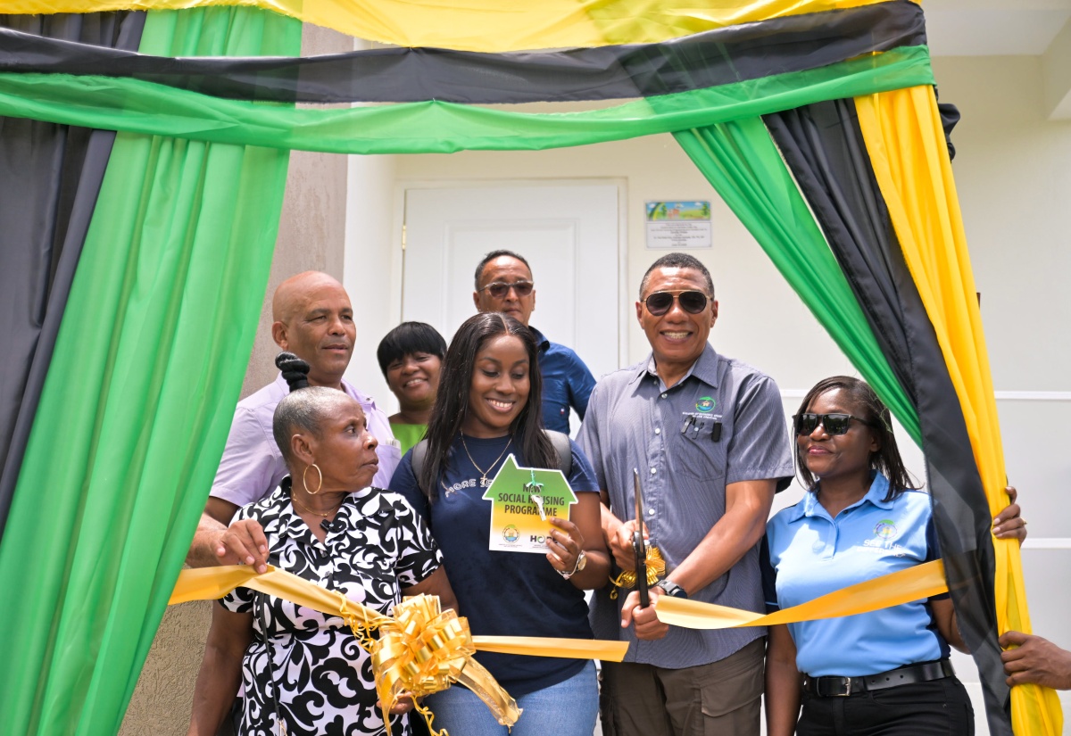 Prime Minister, Dr. the Most Hon. Andrew Holness (second right, front row), cuts the ribbon during a handover ceremony on June 19 for a three-bedroom house presented to New Social Housing Programme (NSHP) beneficiary, Jennifer Phillips (left, front row), and her daughter, Alecia Deer (second left, front row) in White Hall, Seaforth, St. Thomas. Also participating are Permanent Secretary in the Ministry of Economic Growth and Job Creation, Arlene Williams (right, front row); and (from left, back row) Member of Parliament for St. Thomas Western, James Robertson; Councillor for the Seaforth Division, Sheroo Stephens; and Mayor of Morant Bay, Councillor Louis Chin.