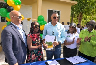 Prime Minister, Dr. the Most Hon. Andrew Holness (centre), hands New Social Housing Programme (NSHP) beneficiary, Elaine Bennett (second left), the social contract and keys to her new house in Lloyd’s District in St. Thomas recently.  Sharing the moment (from left) are Member of Parliament for St. Thomas Western, James Robertson; Permanent Secretary in the Ministry of Economic Growth and Job Creation, Arlene Williams; and Minister of Local Government and Community Development, Hon. Desmond McKenzie.