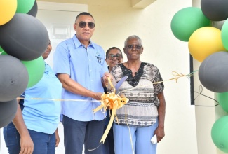 Prime Minister, Dr. the Most Hon. Andrew Holness (centre) cuts the ribbon to officially hand over a new three-bedroom unit to New Social Housing Programme (NSHP) beneficiary, Ivylin Thompson (right). The occasion was the handover ceremony for the unit in Brampton District, Trelawny on Friday (June 6). Sharing in the moment are Chairperson of the NSHP Oversight Committee, Judith Robb Walters (partially hidden, left) and Member of Parliament for Trelawny Southern, Marisa Dalrymple Philibert.