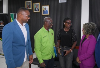 Minister of Local Government & Community Development, Hon. Desmond McKenzie (second left);Minister of Education, Skills, Youth and Information, Senator Dr. the Hon. Dana Morris Dixon (right), and Social Development Commission (SDC) Executive Director, Omar C. Frith (left), listen to nail technician Charma-Kay Barrett, following a recent entrepreneurship grants presentation ceremony at the Ministry’s office in Kingston. One hundred entrepreneurs received grants under the Social Development Commission  (SDC) Local Economic Development Support Programme (LEDSP).