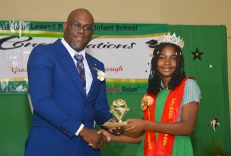 Principal of the Manchester-based Christiana Leased Primary School, Aldayne Porter (left), makes a presentation to Top Student, Ri-Channe Thomas, at the school’s recent graduation ceremony held at the Sacred Heart Academy in the parish. 