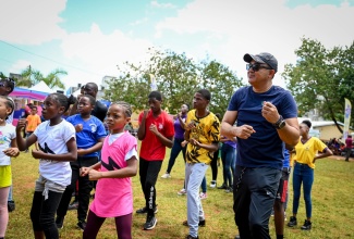 Minister of Health and Wellness, Dr. the Hon. Christopher Tufton, goes through an exercise routine with students at a National School Moves Day event at Manchester High School in Mandeville in April 2024.
