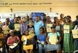 Minister of Agriculture, Fisheries and Mining, Hon. Floyd Green (centre), shares a moment with south St. Elizabeth farmers, who have received land titles under the Pedro Plains Irrigation Expansion Project. The documents were handed over on Tuesday (July 22) at the Newell High School in the parish.