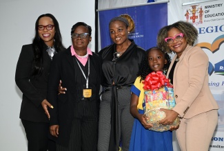 Minister of Education, Skills, Youth and Information, Senator Dr. the Hon. Dana Morris Dixon (right), presents a special gift basket to student of Barking Lodge Primary and Infant School in St. Thomas, Cordelia Nicholson, who achieved 100 per cent in Language Arts in the Primary Exit Profile (PEP) exam, at a Back-to-School Conference for Principals and Vice-principals from Region 2 (Portland, St. Thomas and St. Mary), held at Hideaway at Royalton Blue Water in Falmouth, Trelawny, on Tuesday, July 15). Sharing the moment (from left) are Permanent Secretary in the Ministry of Education, Skills, Youth and Information, Dr. Kasan Troupe; Principal of Barking Lodge Primary and Infant School, Tannia Johnson; and Language Arts teacher of Barking Lodge Primary and Infant School, Tracia Ann Hunt-Sylva.