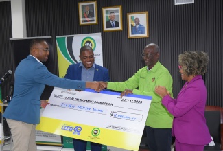 Minister of Local Government & Community Development, Hon. Desmond McKenzie (second right), hands over a cheque to Social Development Commission (SDC) Executive Director, Omar C. Frith (left), during a special entrepreneurship grants presentation ceremony at the Ministry’s office in Kingston, on Thursday (July 17). Also participating in the handover are Minister of Education, Skills, Youth and Information, Senator Dr. the Hon. Dana Morris Dixon (right) and Chairman of SDC’s Board, Hidran McKulsky. One hundred entrepreneurs received grants under the SDC’s Local Economic Development Support Programme (LEDSP).