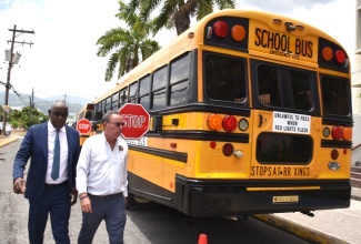 Minister of Science, Energy, Telecommunications and Transport, Hon. Daryl Vaz (right), and Managing Director of the Jamaica Urban Transit Company (JUTC), Owen Ellington, walk alongside one of the recently procured units under the rural school bus system. The event was Tuesday’s (July 8) press conference to give an update on the system, at the Petroleum Corporation of Jamaica (PCJ) auditorium, in Kingston.

