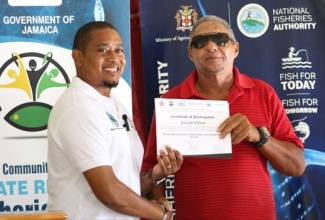 Minister of Agriculture, Fisheries and Mining, Hon. Floyd Green (left), presents a certificate of participation to fisher Joseph Elliot, during a Pelagic Sub-Project handover and awards ceremony at Billy’s Bay Fishing Village in Treasure Beach, St. Elizabeth on Friday (July 18).

