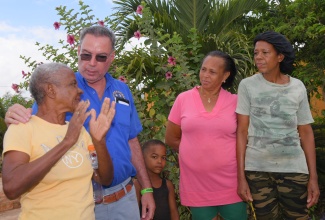 Minister of Science, Energy, Telecommunications and Transport, Hon. Daryl Vaz (second left), engages with resident of Comma Pen in St. Elizabeth, Muriel Freeman (left), during a visit to the community on Thursday (July 10) to observe house wiring and pole extension activities under the Community Electrification Project. Looking on (from centre) are fellow community members Ojanie Thomas; Marcia Morgan (second right) and Bobbette Sinclair.