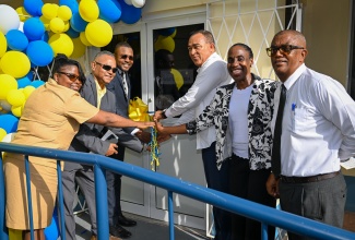 Minister of Health and Wellness, Dr. the Hon. Christopher Tufton (third right), and Member of Parliament for Clarendon North Central, Hon. Robert Morgan (third left), lead in the cutting of the ribbon for the official handover of the refurbished Darlow Health Centre, in Clarendon, on July 17. Others pictured (from left) are Public Health Nurse for the Mocho Health District, Anita Dwyer; Vice Chairman of the Southern Regional Health Authority (SRHA), Michael Stern; Director for Facilities Operations and Maintenance at the SRHA, Herschel Ismail; and Parish Manager for Clarendon Health Services, Joseph Grant.
