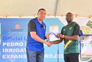 Prime Minister, Dr. the Most Hon. Andrew Holness (left), presents farmer, Kevin Lindo, with his land title, during the ground-breaking ceremony for the Pedro Plains Irrigation Expansion Project in Short Hills, St. Elizabeth on Friday (July 11). 
