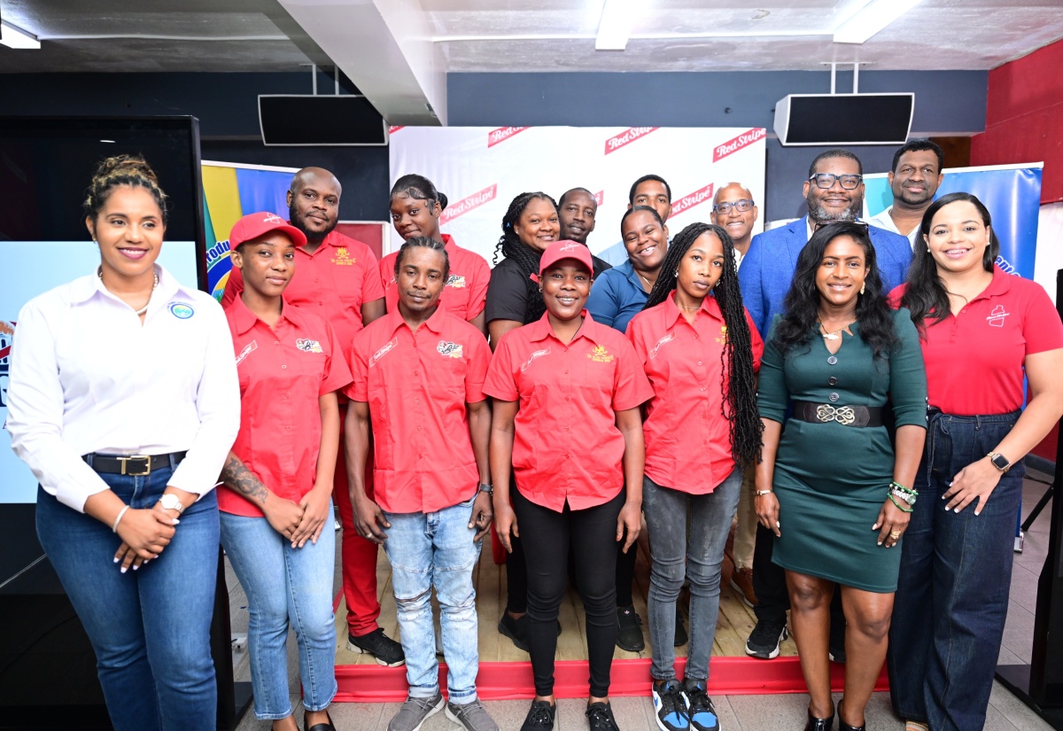 Tourism Product Development Company Limited (TPDCo) Executive Director, Wade Mars (second row, right), shares lens with trainee bartenders who will benefit from the Port Royal Saloon Waters Tour following the signing of a Memorandum of Understanding between TPDCo and Red Stripe on Monday (August 25). The MOU represents an agreement between the two entities to collaborate on the development of the Port Royal Saloon Waters Tour. They are joined by Brand Manager of Red Stripe and Dragon Stout, Amoye Phillpotts-Brown (front row, right); TPDCo Destination Manager for Kingston, Mikisha Silvera (front row, second right); and TPDCo Director of Product Development and Community Tourism, Kerry-Ann Lowe (front row, left). The signing of the MOU took place at Red Stripe’s Spanish Town Road headquarters in Kingston.