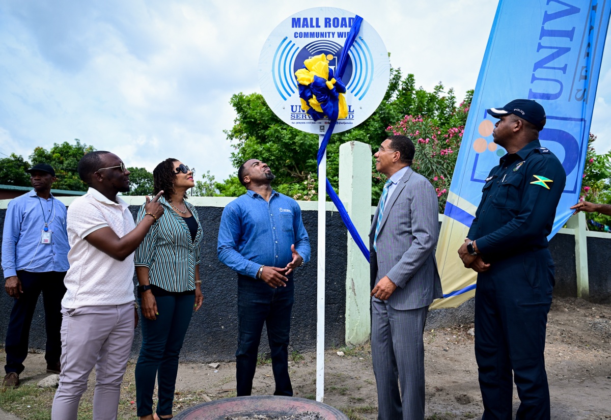 Prime Minister, Dr. the Most Hon. Andrew Holness (second right), unveils the official sign to commission the Mall Road community Wi-Fi hotspot in St. Andrew West Central on Thursday (July 31). Dr. Holness serves as the constituency’s Member of Parliament. He is joined by Minister without Portfolio in the Office of the Prime Minister with Responsibility for Efficiency, Innovation and Digital Transformation, Senator the Hon. Ambassador Audrey Marks (second left); and (from left) Councillor/Caretaker, Olympic Gardens Division, Kelvin Hall; Chief Executive Officer, Universal Service Fund (USF), Charlton McFarlane; and Commanding Officer, St. Andrew South Division, Senior Superintendent of Police Damion Manderson.