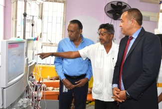 Minister of Health and Wellness, Dr. the Hon. Christopher Tufton (right), and Culture, Health, Arts, Sports and Education (CHASE) Fund Chief Executive Officer, W. Billy Heaven (left), are shown a display on a haemodialysis machine by Consultant Nephrologist at the Kingston Public Hospital (KPH), Dr. Basil Babolal. The machine is one of 10  donated to the KPH by the CHASE Fund.  

