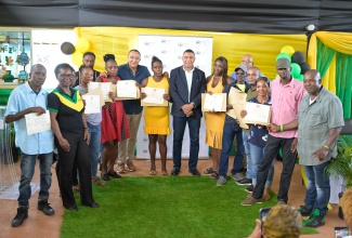 Prime Minister, Dr. the Most Hon. Andrew Holness (center), along with Minister of Health and Wellness and Member of Parliament for West Central St. Catherine, Dr. the Hon. Christopher Tufton (seventh left), with residents of Naseberry Villa, who received their land titles from the Housing Agency of Jamaica (HAJ), during a ceremony in St. Catherine on August 5.