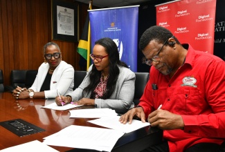 Permanent Secretary in the Ministry of Education, Skills, Youth and Information, Dr. Kasan Troupe (centre) and President of the College of Agriculture, Science and Education (CASE) in Portland, Dr. Derrick Deslandes (right), sign a Memorandum of Understanding (MoU) for the installation of a smart lab at the institution, while Chairman of Digicel Foundation, Joy Clark (left), looks on. The MoU was signed on Friday (Aug. 15) at the Ministry’s Heroes Circle headquarters in Kingston.  Under the agreement, a smart lab will also be established at Church Teachers’ College in Manchester.