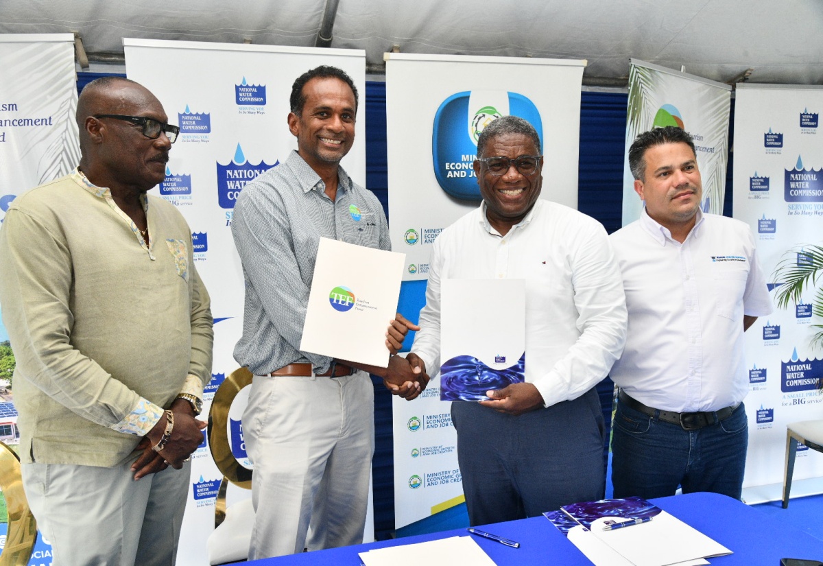 National Water Commission (NWC) Regional Manager for Portland, Richard Williams (second right) and Executive Director of the Tourism Enhancement Fund (TEF), Dr. Carey Wallace (second left), shake hands following the signing of the Financing Agreement for the $22-million Carder Park Wastewater Project in Port Antonio, Portland, on Wednesday (August 20), in Carder Park. Sharing the moment are Minister without Portfolio in the Ministry of Economic Growth and Job Creation, Hon. Matthew Samuda (right), and Mayor of Port Antonio, Councillor Paul Thompson.