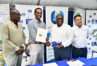 National Water Commission (NWC) Regional Manager for Portland, Richard Williams (second right) and Executive Director of the Tourism Enhancement Fund (TEF), Dr. Carey Wallace (second left), shake hands following the signing of the Financing Agreement for the $22-million Carder Park Wastewater Project in Port Antonio, Portland, on Wednesday (August 20), in Carder Park. Sharing the moment are Minister without Portfolio in the Ministry of Economic Growth and Job Creation, Hon. Matthew Samuda (right), and Mayor of Port Antonio, Councillor Paul Thompson. 