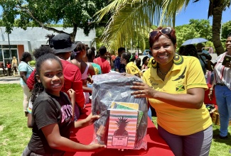 Minister at Alleluia Ministries International (AMI), Nichole Chattoo (right), presents a backpack and school supplies to Jaida Gardner during a Back-to-School Outreach at Harmony Beach Park, Montego Bay, St James, on Saturday (August 16).

