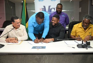 Minister of State in the Office of the Prime Minister (West) and Member of Parliament for St. James Southern, Hon. Homer Davis (left) and Chairman of the St. James Municipal Corporation and Mayor of Montego Bay, Councillor Richard Vernon (second right), look on as Director of Planning and Acting Chief Executive Officer of the St. James Municipal Corporation, Trevian Manning (second left), signs the contract for the $23 million rehabilitation of the Richmond Hill Road in Catadupa, at the Corporation in Montego Bay on Wednesday (July 30). Managing Director of Build Management Technologies and Logistics, Andrew Jeffery (right), also affixes his signature to the contract, while the Corporation’s Acting Chief City Engineer, Yannick Beckford, observes.