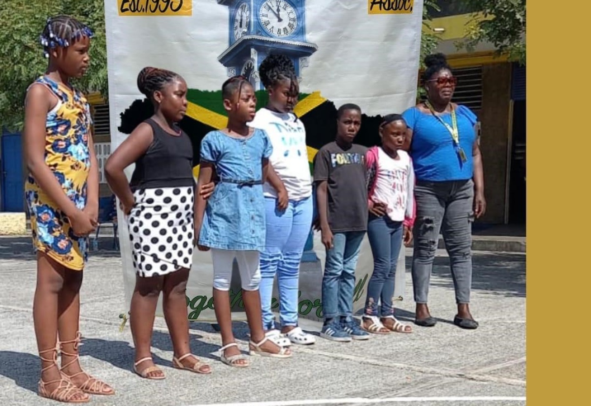 Member of the Old Harbour and Friends Association (OHFA), Loris Foreman (right), shares a photo opportunity with some of the students who received donation of school supplies, scholarships and cash grants, during a recent outreach event held at the Old Harbour Primary School in St. Catherine.

