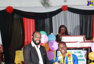 Top Male Student at the St. Catherine based White Marl Primary and Infant School, Nathan Downer (right), receives his trophy from past student of the school, Joseph Willis, at the institution’s recent graduation ceremony, held at the New Testament Church of God in the community.
