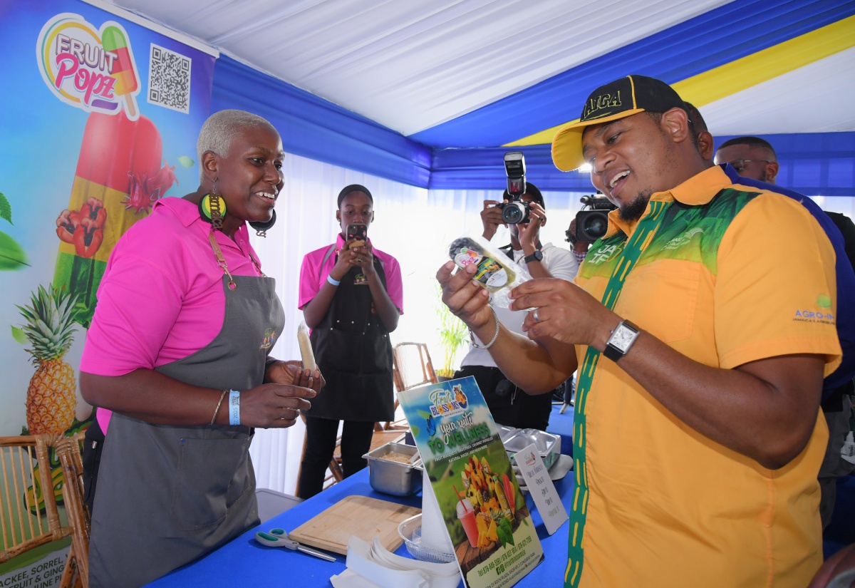Minister of Agriculture, Fisheries and Mining, Hon. Floyd Green (right) looks at a product on offer at the Fruit Blossoms booth, while entrepreneur Kadeen Harvey looks on. Minister Green went on a tour of booths at the 71st staging of the Denbigh Agricultural, Industrial and Food Show at the Denbigh Showground in May Pen, Clarendon on Saturday (Aug. 2).

 