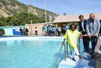 Minister of Culture, Gender, Entertainment and Sport,  Hon. Olivia Grange (left), dips her feet into the healing waters of the Rockfort Mineral Bath in Kingston, following its reopening on Thursday (August 21). Observing are (from second left) Managing Director of Caribbean Cement Company Ltd., Jorge Martinez, and Chairman of the Jamaica National Heritage Trust (JNHT), Orville Hill.


