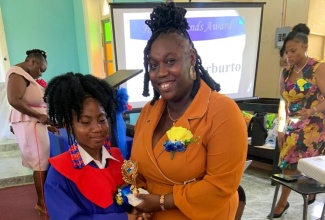 Top Student at the Portland based Birnamwood Primary School, Abigail Warburton (left), receives her trophy from teacher at the school, Anny-K Lafayette, during the institution’s recent graduation ceremony, held at the St. James Anglican Church in the parish.

