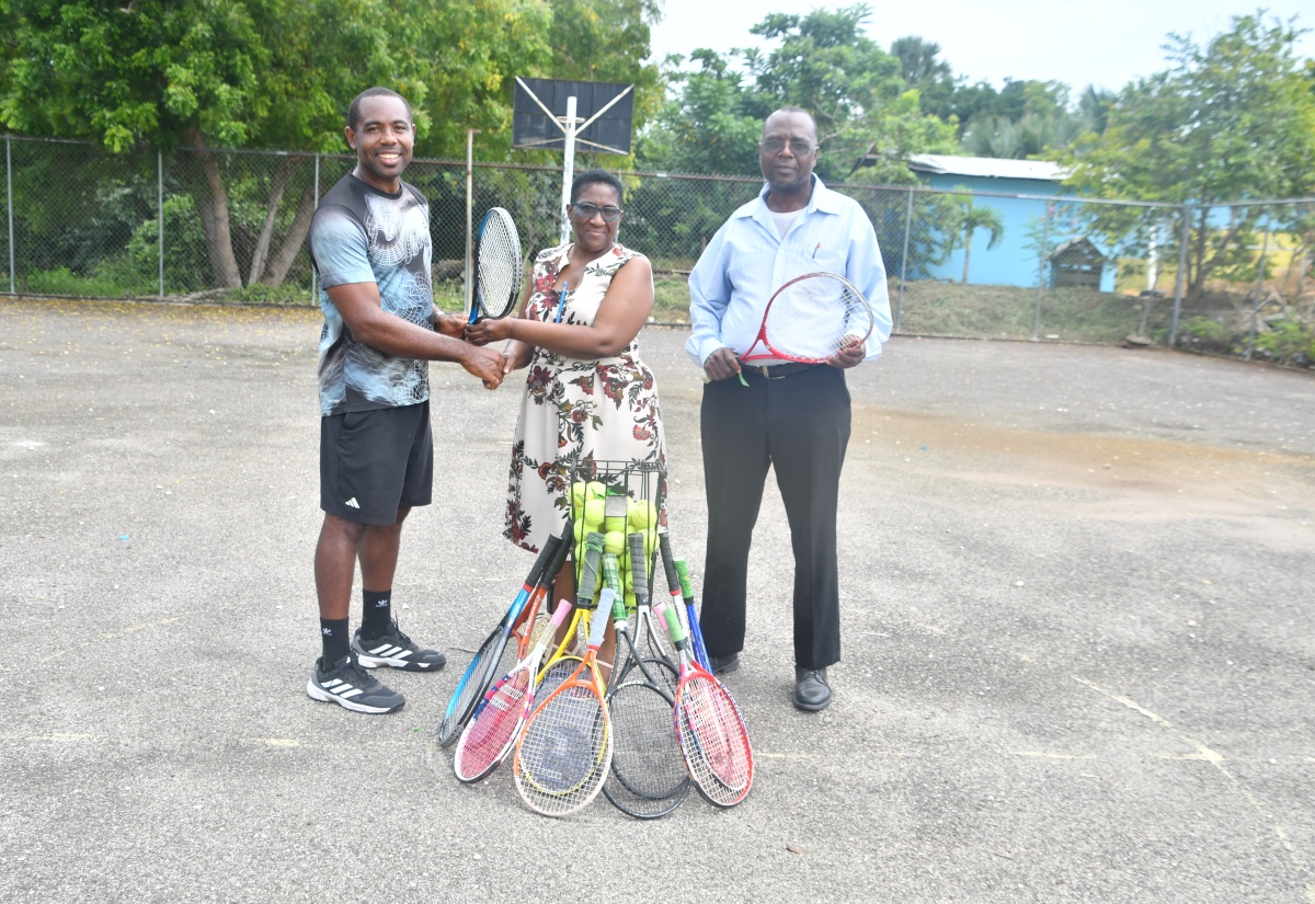 Tennis instructor Kevin Simms (left) hands over tennis equipment to Principal of Broughton Primary in Westmoreland, Marva Davis-Clarke, at the school on Thursday (August 28).  The donation is aimed at bolstering the school's Jamaica Moves in School activities. Sharing the moment is Health Promotion and Education Officer for Westmoreland, Gerald Miller, who aids in spearheading the Jamaica Moves in School initiative in primary schools across the parish.